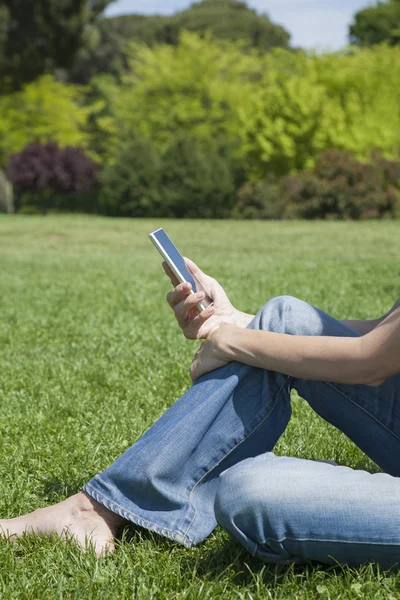 Frau händigt Handy im Park aus — Stockfoto