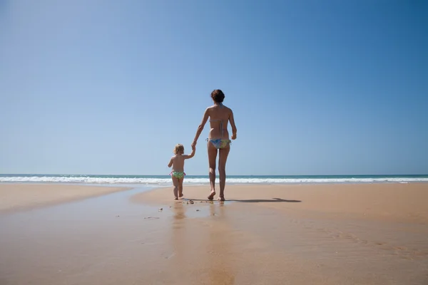 Bebé y madre tomados de la mano caminando al océano — Foto de Stock