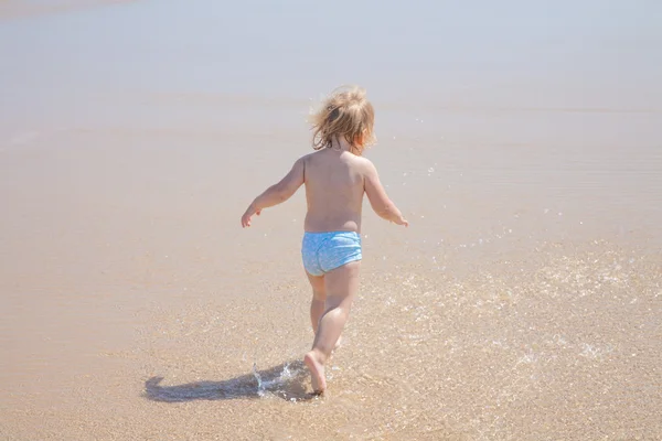 Tillbaka baby körs vid havsstranden — Stockfoto