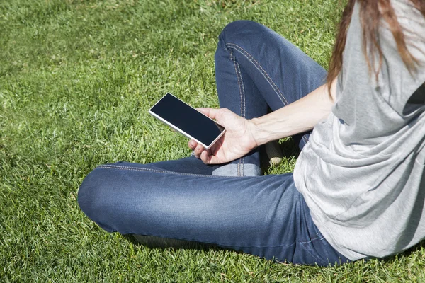 Frau mit leerem Bildschirm telefoniert im Gras — Stockfoto