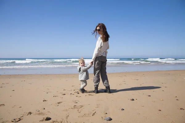 Madre y bebé tomados de la mano en la playa — Foto de Stock