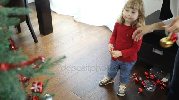 enfant plaçant la boule rouge dans l'arbre de Noël 