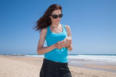 mavi gömlek kadın cep telefonuyla kumsalda