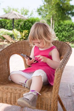 cep telefonu izlemek hasır sandalye üzerinde oturan küçük kız