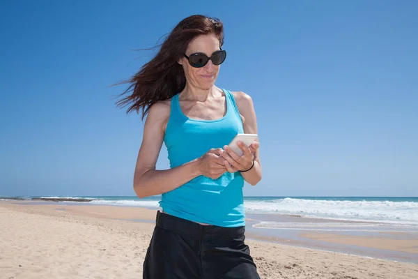 Mulher camisa azul usando telefone celular na praia — Fotografia de Stock