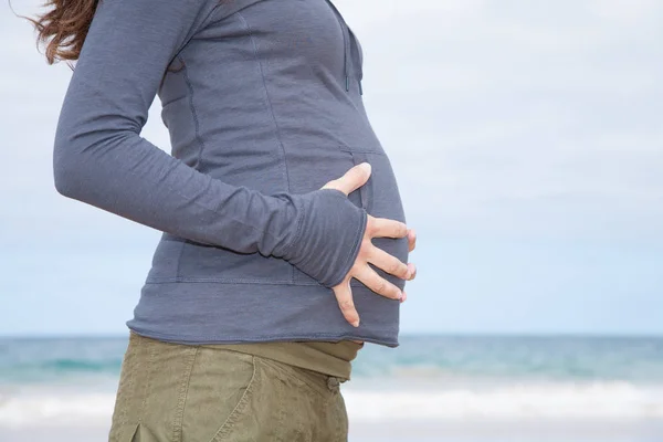 Détail des mains sur le ventre chemise grise enceinte — Photo