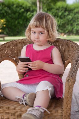 cep telefonu görünümlü hasır sandalye üzerinde oturan küçük kız