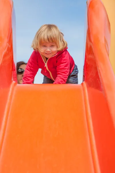 Baby playing in orange slide — Stock Photo, Image