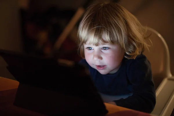child enjoying watching screen at night.