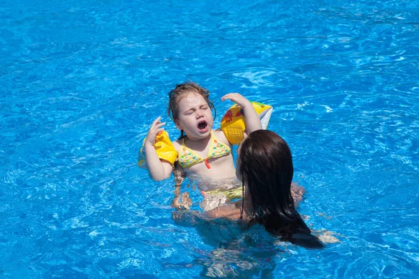 Litet barn i mor händer gestikulerande i poolen — Stockfoto