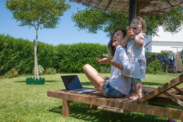 Śmieszne kobieta z laptopa i małe dziecko w ogrodzie — Zdjęcie stockowe