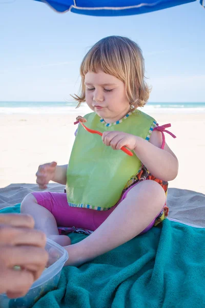 Bambino mangiare giù ombrellone in spiaggia — Foto Stock