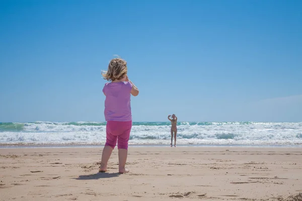 Mamma på havsstranden ringa liten flicka på stranden — Stockfoto