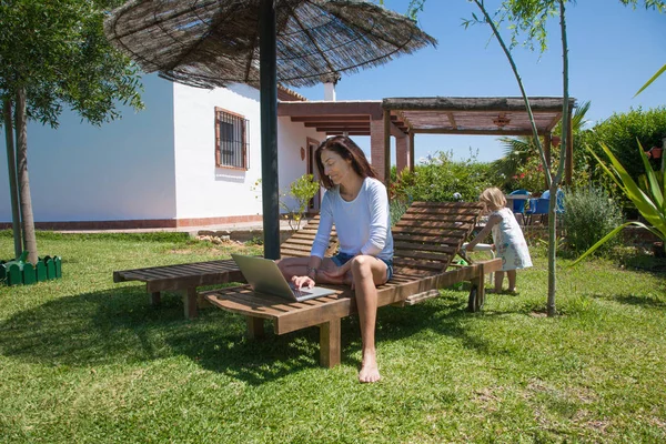 Dizüstü bilgisayar ve küçük çocuk Garden'da kullanan kadın — Stok fotoğraf