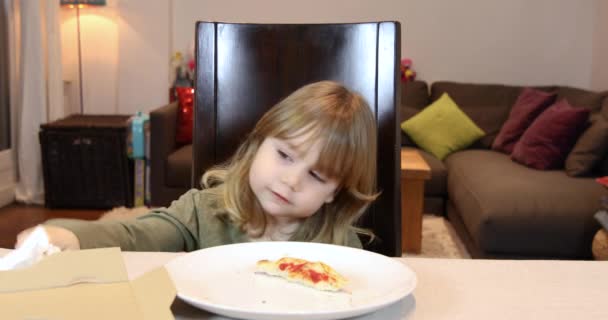 Klein kind eten van pizza en lachen thuis — Stockvideo