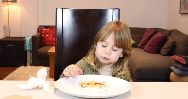 Маленький ребенок ест пиццу дома — стоковое видео