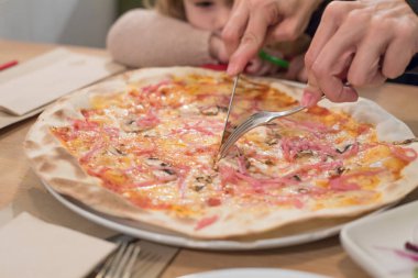 Anne arayan çocuk çatal ve bıçak kesim pizza eller