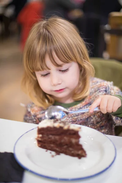 Criança comer pedaço de bolo de chocolate no restaurante — Fotografia de Stock