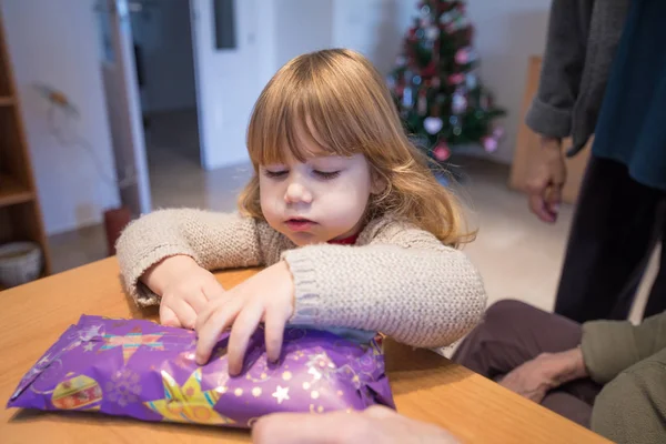 Ребенок ищет, чтобы открыть рождественский подарок завернутый в бумагу — стоковое фото