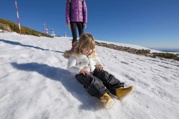 Zittend op sneeuw naast moeder kind — Stockfoto