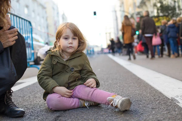 Плачущий маленький ребенок сидит на асфальтовой улице — стоковое фото