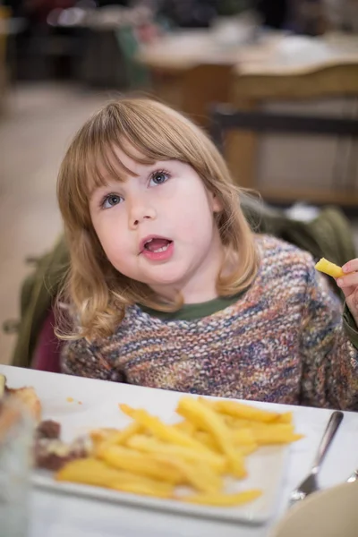Criança comendo batatas fritas com a mão — Fotografia de Stock