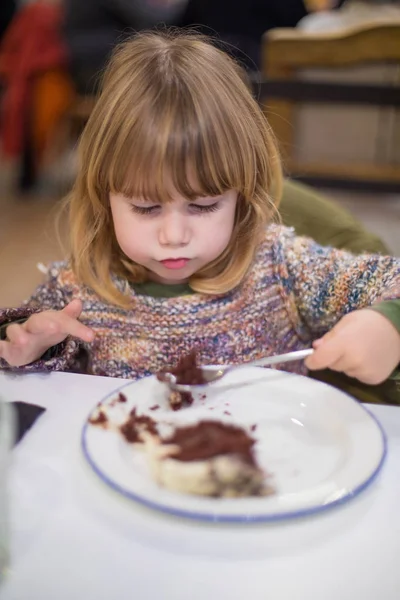 Criança com colher comer bolo de chocolate — Fotografia de Stock