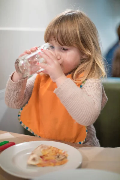 Criança bebendo copo de água no restaurante pizza — Fotografia de Stock