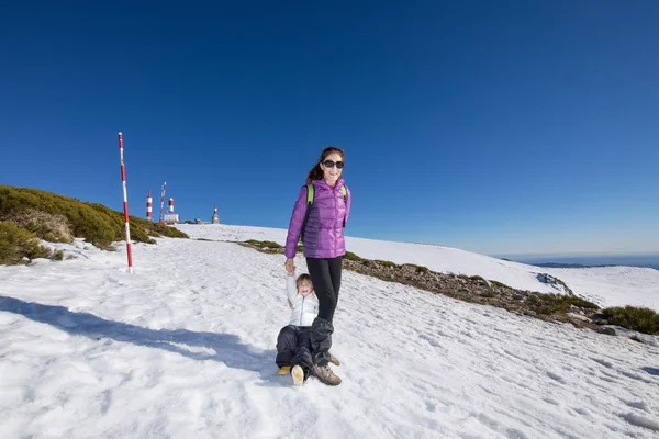 Mor och barn som ler i snow mountain toppmötet — Stockfoto