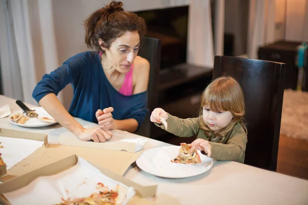 Child surprise face with a pizza broken piece with mother — Stock Photo, Image