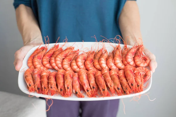 Woman hands showing cooked red prawns on white tray — Stock Photo, Image