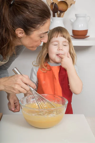 Child tasting whipped cream next to mother — Stock Photo, Image