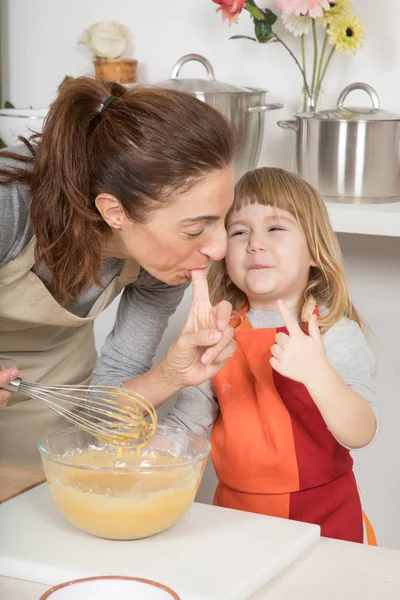 Divertida madre y el niño saboreando crema batida con el dedo — Foto de Stock