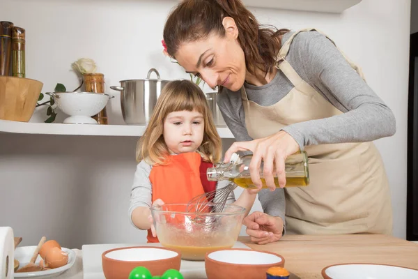 Frau und Kind kochen und gießen Öl in Schüssel — Stockfoto