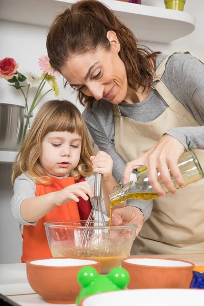 Woman pouring oil in bowl and child whipping — Stock Photo, Image