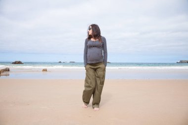 gri kazak kumsalda yürürken hamile