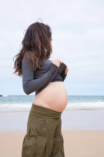 Pregnant at beach showing tummy — Stock Photo, Image