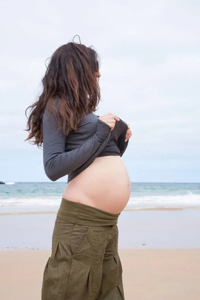 Grávida na praia mostrando barriga — Fotografia de Stock