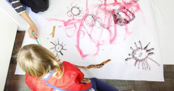 Воздушный вид на ребенка и женщину, рисующих вместе на полу — стоковое видео