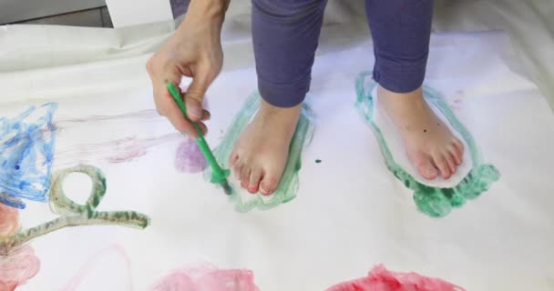 Μητέρα ζωγραφική περίγραμμα των ποδιών του παιδιού με πράσινο ακουαρέλα — Αρχείο Βίντεο