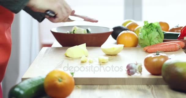 Руки человека, режущего яблоко на деревянной доске — стоковое видео