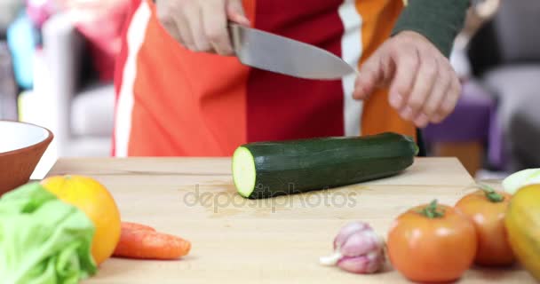 Hands of man cutting zucchini on wooden cutting board — Stock Video