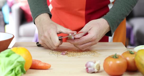 Hands of man peeling garlic on wooden cutting board — Stock Video