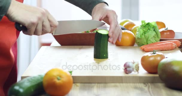 Hombre cortando calabacín en tabla de cortar de madera — Vídeo de stock