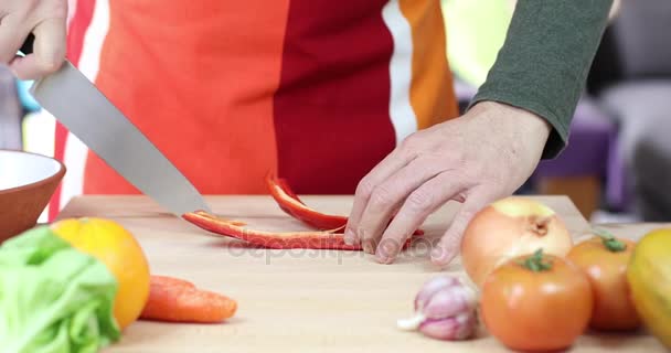 Man skräder röd paprika på trä skärbräda — Stockvideo