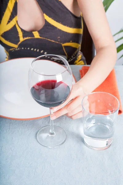Γυάλινο φλιτζάνι κρασί σε γυναίκα με το χέρι στην μπλε τραπεζομάντιλο — Φωτογραφία Αρχείου