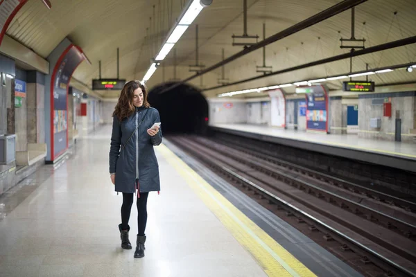 Donna che cammina nella piattaforma della metropolitana utilizzando il telefono — Foto Stock