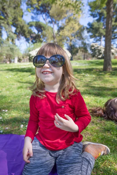 Dítě hrající s dospělého sluneční brýle v parku — Stock fotografie