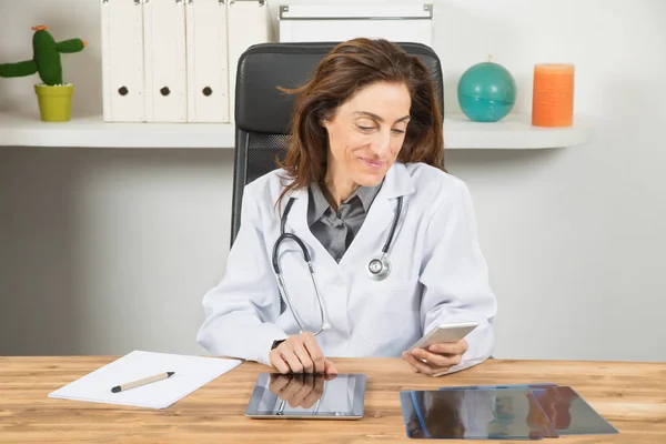 Doktor žena čte mobilní telefon v kanceláři — Stock fotografie