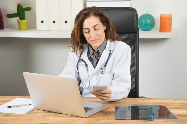 Doctor woman using phone and computer — Stock Photo, Image